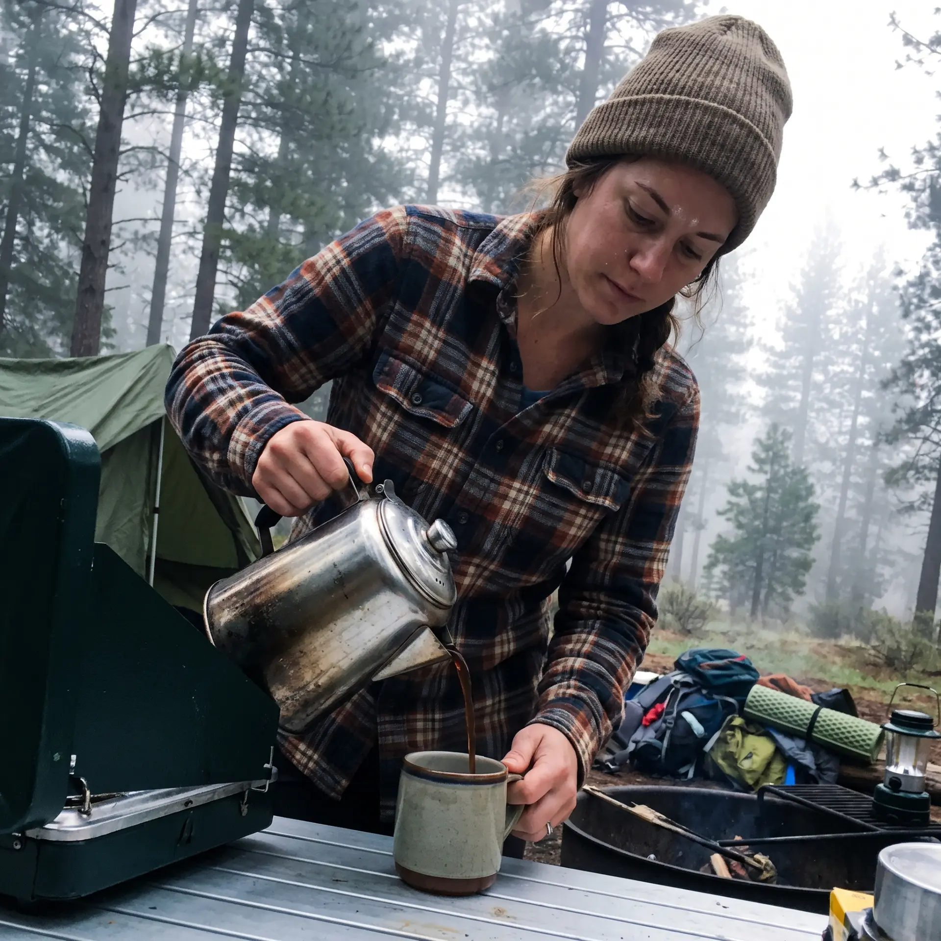 Camper pouring percolator coffee on a foggy morning